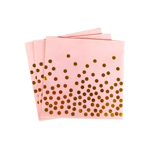 Dettaglio in primo piano di tovaglioli di carta rosa con pois dorati per compleanni.