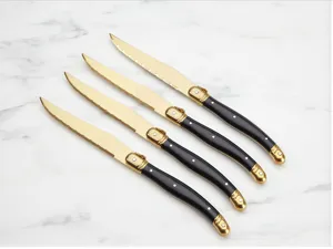 Set di 4 coltelli da bistecca in acciaio dorato con manico nero e dettagli classici.