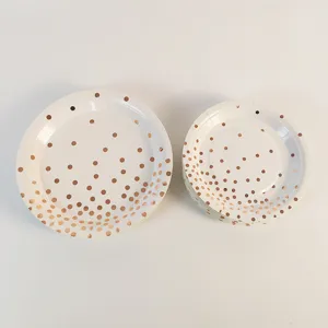 Vista dettagliata di piatti di carta usa e getta bianchi con eleganti pois oro rosa