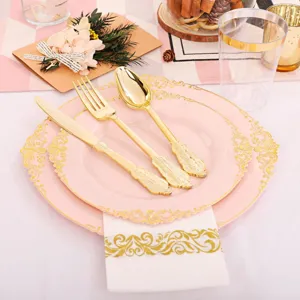 Détail d'assiettes roses à bord doré et ensemble de couverts en plastique doré.