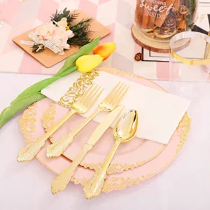 Gros plan d'une assiette de fête en plastique rose avec motif doré et set de couverts assorti.