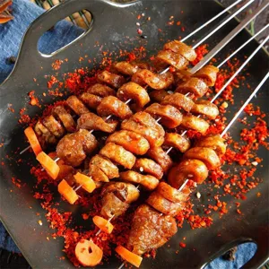 Detaillierte Nahaufnahme von gewellten Edelstahl-Grillspießen mit Grillgut und Gewürzen