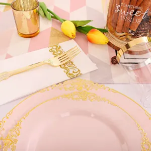 Gros plan d'une assiette en plastique rose avec bord doré et ensemble de couverts dorés