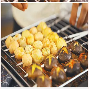 Detailansicht von flachen Edelstahl-Grillspießen mit Fleischbällchen auf einem Grill