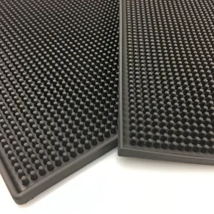 Macro view of black studded PVC bar mat showing the non-slip drainage texture and thick rubber material