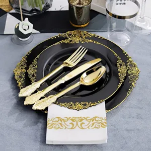 Détail d'assiettes en plastique noir avec bordure dorée et couverts dorés