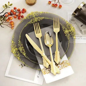 Gros plan d'un ensemble de couverts dorés jetables sur des assiettes grises.