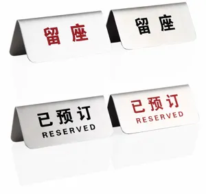 Detalle de carteles de mesa reservados en acero inoxidable con texto chino e inglés.