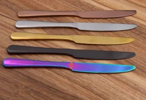 Five colorful stainless steel steak knives with serrated blades on wooden surface