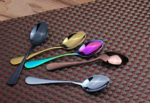 Close-up of five colorful stainless steel spoons with a mirror finish on a mat