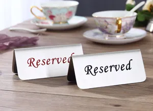 Letreros de mesa reservados profesionales de acero inoxidable en una mesa de café