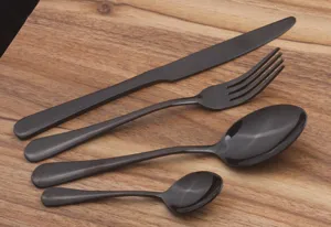 Detailed view of 4-piece black stainless steel cutlery set on a wooden table surface