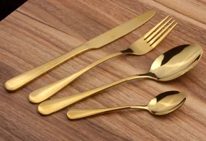 Detailed view of 4-piece gold stainless steel cutlery set on wood surface
