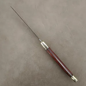 Laguiole steak knife with wood handle and brass bolsters on gray background.