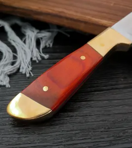 Dettaglio ravvicinato del manico di un coltello in acciaio al carbonio con legno rosso e ottone.