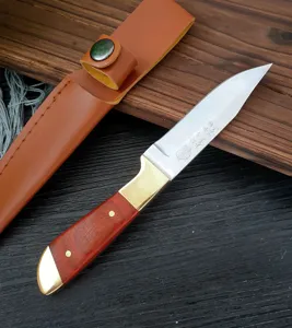 Vista dettagliata di un coltello artigianale in acciaio al carbonio con manico in legno e fodero