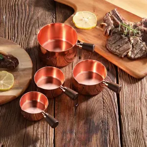 Detail of rose gold stainless steel sauce cups with walnut wood handles in rustic setting