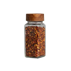 Pot à épices en verre carré avec un couvercle en bois d'acacia et des flocons de piment rouge