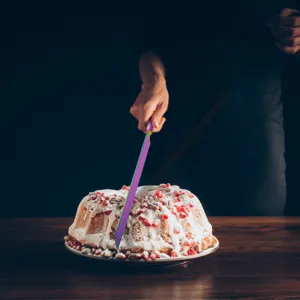 Detailed view of an iridescent rainbow stainless steel knife cutting a frosted cake