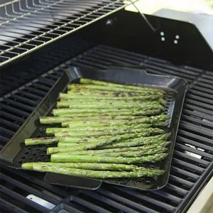 Detailaufnahme einer perforierten Emaille-Grillschale mit Spargel auf einem Grillständer