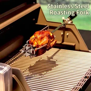 Detailed view of stainless steel rotisserie spit roasting a whole chicken on a grill.
