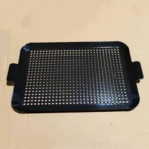 Draufsicht auf eine schwarze, perforierte Emaille-Grillschale mit zwei Griffen.