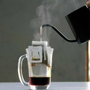 Mattschwarze Handkanne aus Edelstahl gießt heißes Wasser in einen Kaffeefilterbeutel.