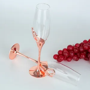 Pair of rose gold heart-shaped champagne flutes with crystal accents for weddings.