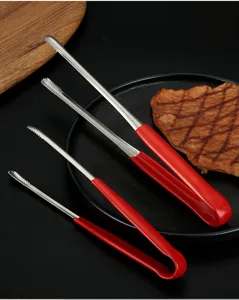 Red handle stainless steel food tongs set for barbecue steak shown on a black plate