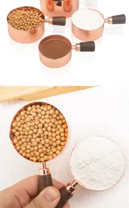 Detailed macro view of rose gold stainless steel measuring cups with walnut wood handles