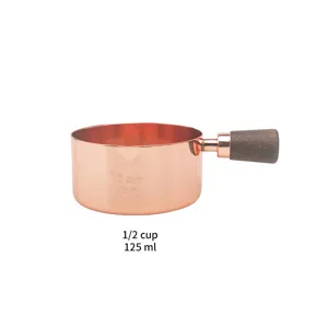 Detailed close-up of a rose gold 125ml measuring cup with a walnut wood handle.