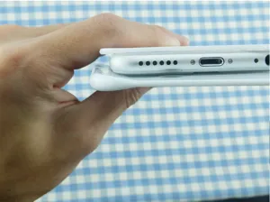 Gros plan montrant l'épaisseur du grattoir à pâte blanc en plastique près d'un téléphone