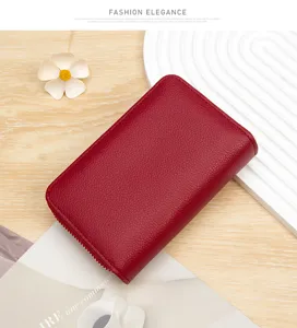 Detail view of a red lychee-textured leather zip-around wallet on a minimalist background