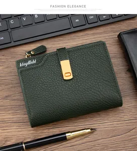 Close-up of green lychee leather women's short wallet with gold hardware on wooden desk.