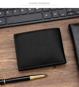 Detailed view of a black pebbled leather men's bifold wallet on a wooden desk environment.