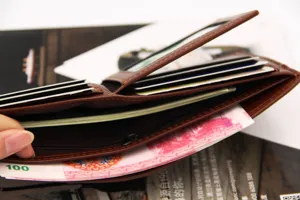 Detailed view of brown men's bifold wallet with multiple card slots and cash