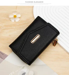 Primer plano de una cartera negra de cuero graneado con elegante detalle de metal dorado.
