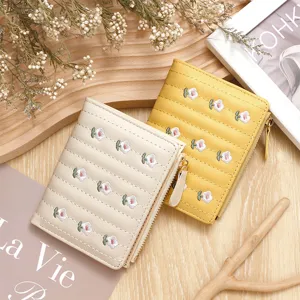 Macro view of delicate small floral embroidery on cream and yellow quilted zip wallets