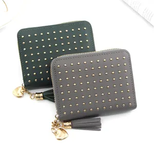 Detailed view of women's mini wallet with gold studs, heart charm, and tassel