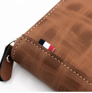 Close-up detail of a brown textured leather men's wallet with a striped ribbon tag