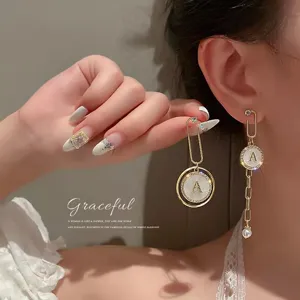 Detailed view of elegant asymmetric gold earrings featuring letter A pendant and pearls