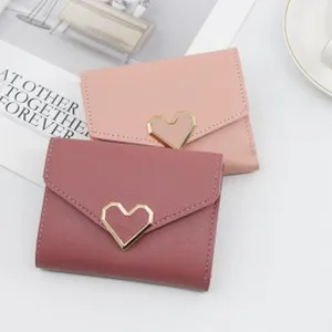 Close-up of pink tri-fold women's wallets featuring elegant gold-toned heart buckles