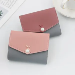 Close-up of two elegant bicolour women's short wallets with unique pearl button details