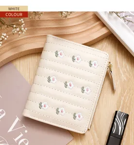 Detailed view of cream embroidered floral women's short zipper wallet on wooden surface
