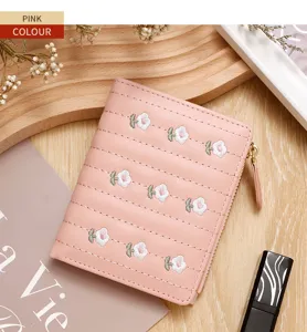 Detailed close-up of pink women's wallet featuring delicate floral embroidery and zipper.