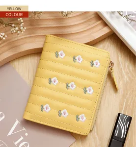 Close-up of a yellow women's short zipper wallet featuring delicate white floral embroidery