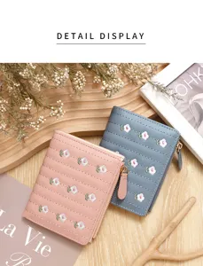 Detail view of two women's short wallets with floral embroidery in pink and blue finish