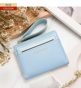Primer plano de una cartera de mujer azul claro con cremallera y correa de muñeca