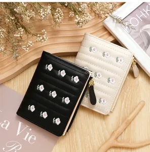 Detailed macro shot of stylish small wallets featuring delicate embroidered flowers and zipper