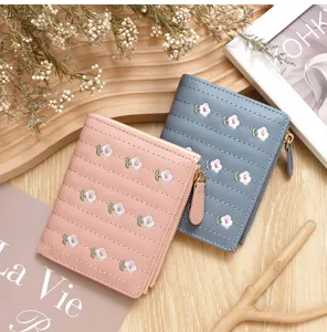 Top view of two small wallets with delicate embroidered flowers in pink and blue colors